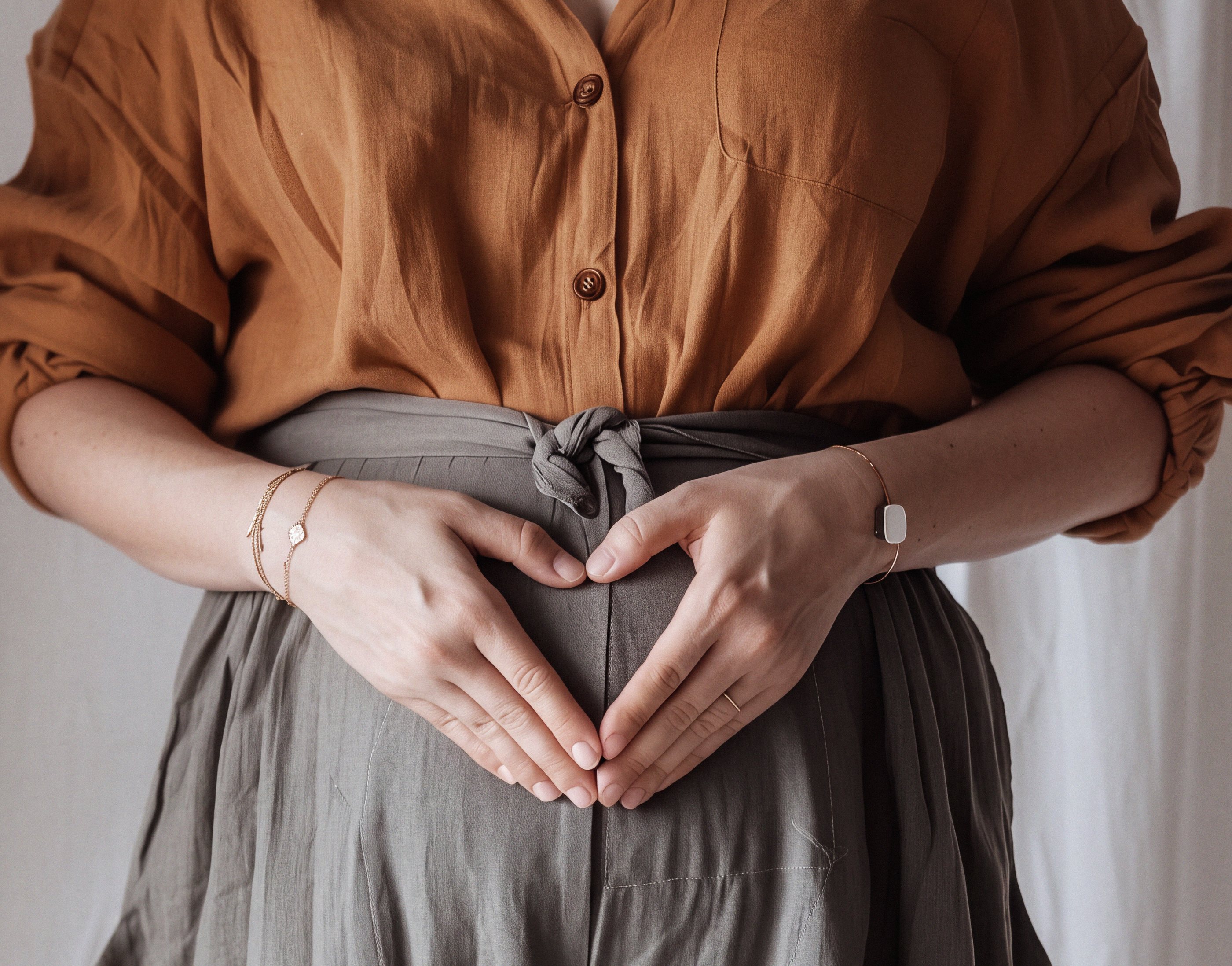 Hands forming a heart shape over the stomach